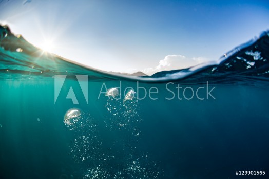 Picture of Ocean water line splits sky and underwaer part Air bubbles in deep blue Bright sun light and blue clear sky